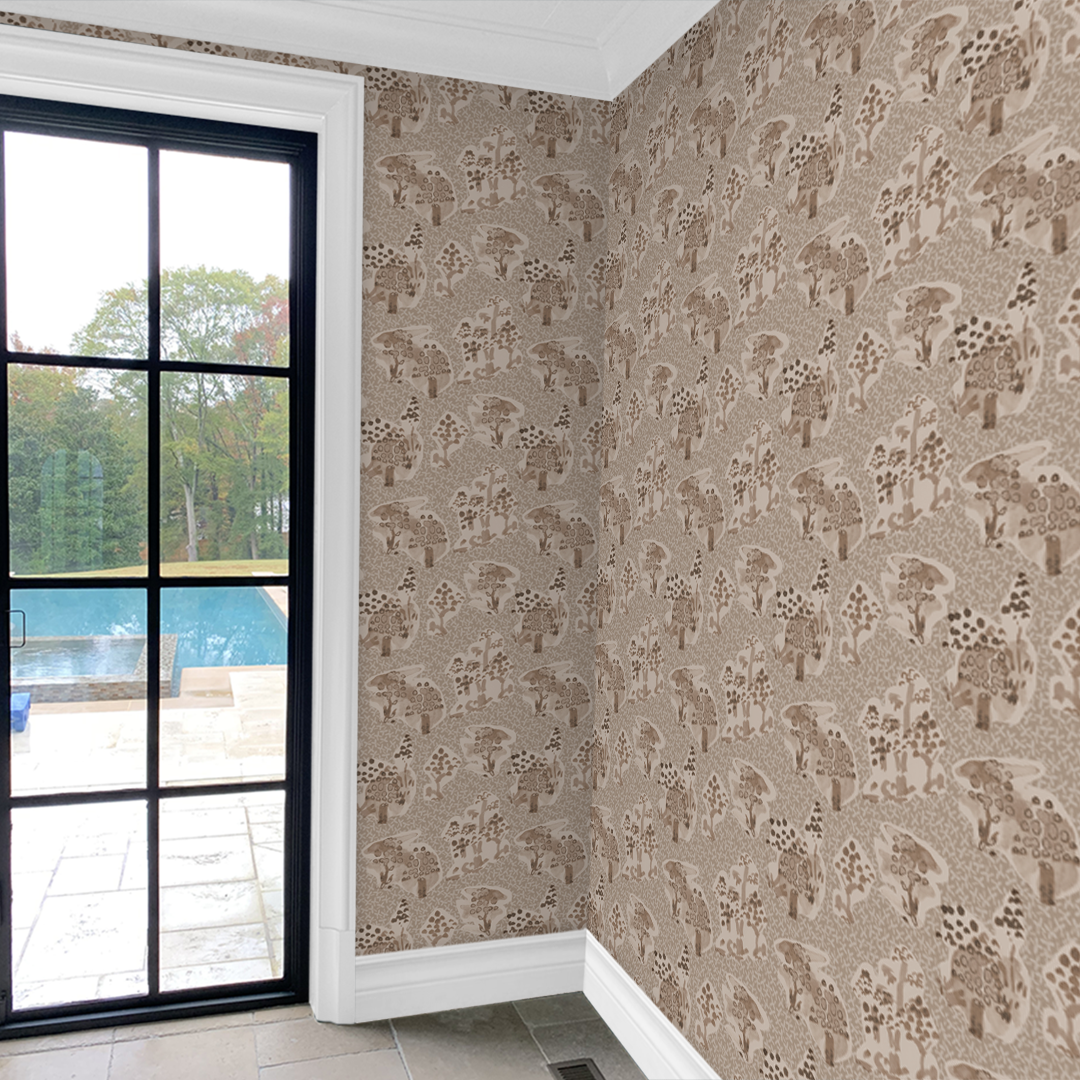 Toile wallpaper by Angela Simeone shown at scale in a room with a black-framed window, warm sand colorway