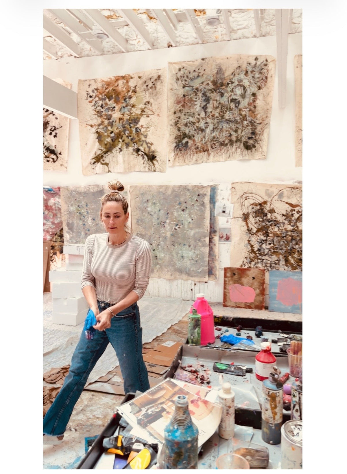 Nashville abstract painter Angela Simeone at work in her studio with several large canvases on the wall behind her, the commission process where two options are painted at once