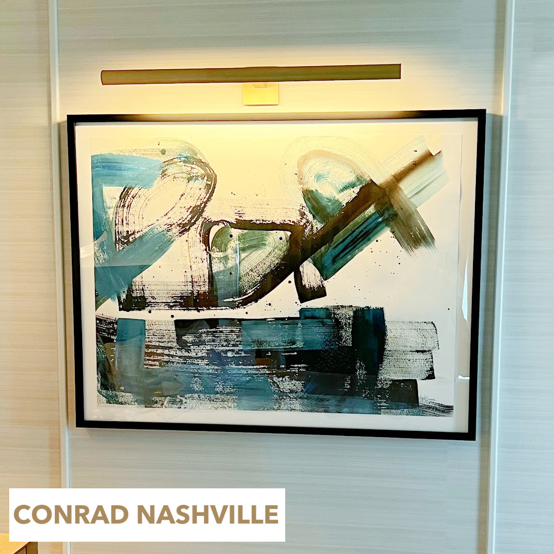 Original abstract painting by Angela Simeone installed directly above a bed, blue palette in a black frame